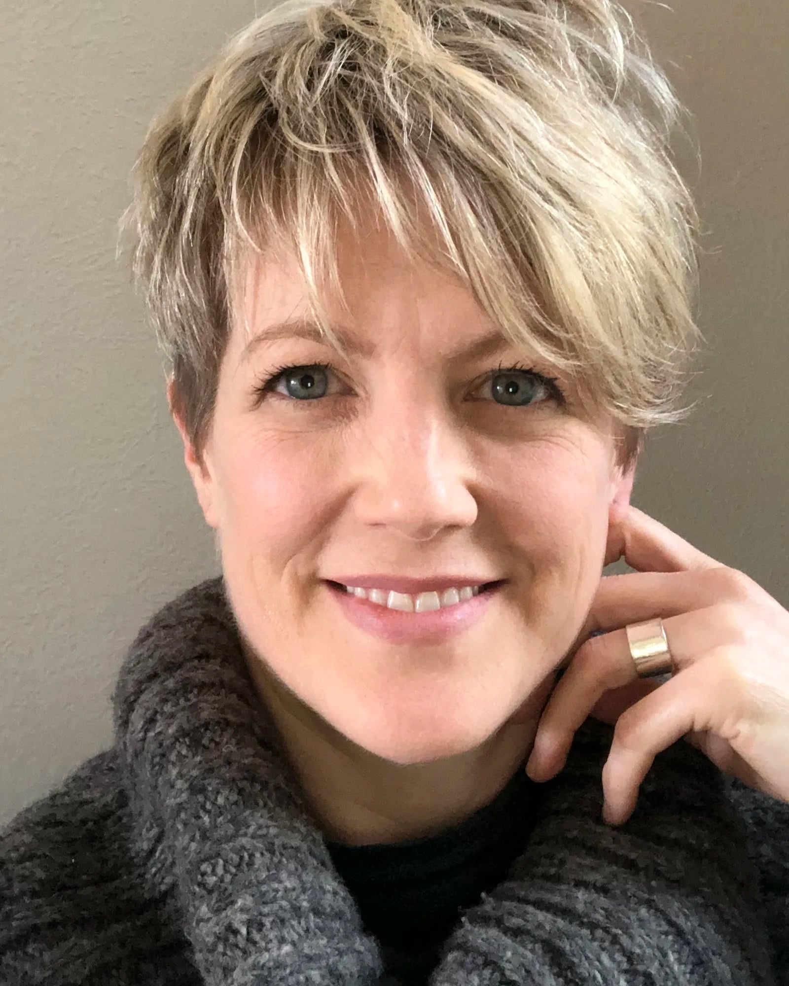 Headshot of Kimberly Jonas wearing a gray sweater against a warm taupe background