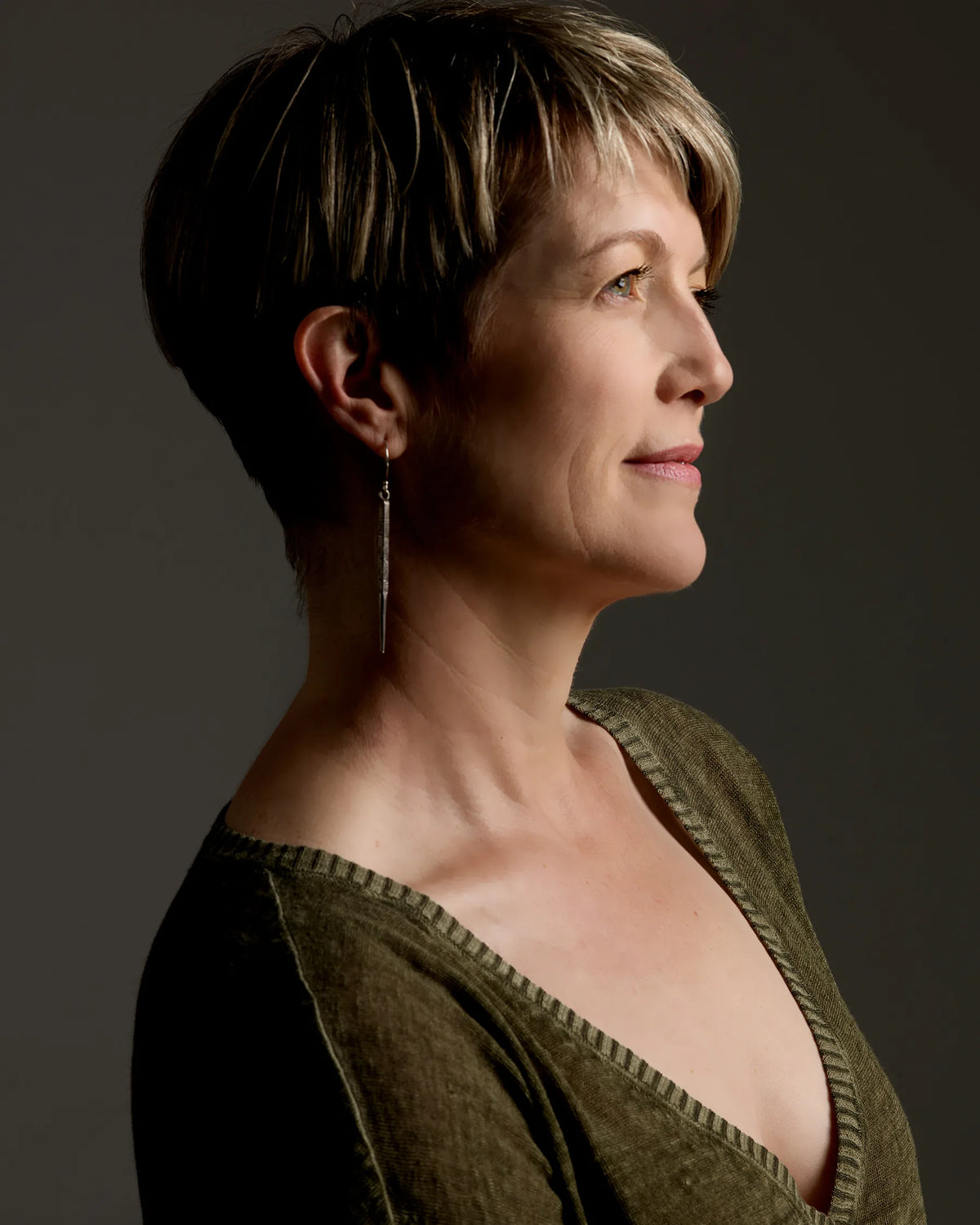 Side profile headshot of Kimberly Jonas wearing a green top against a green-gray background.