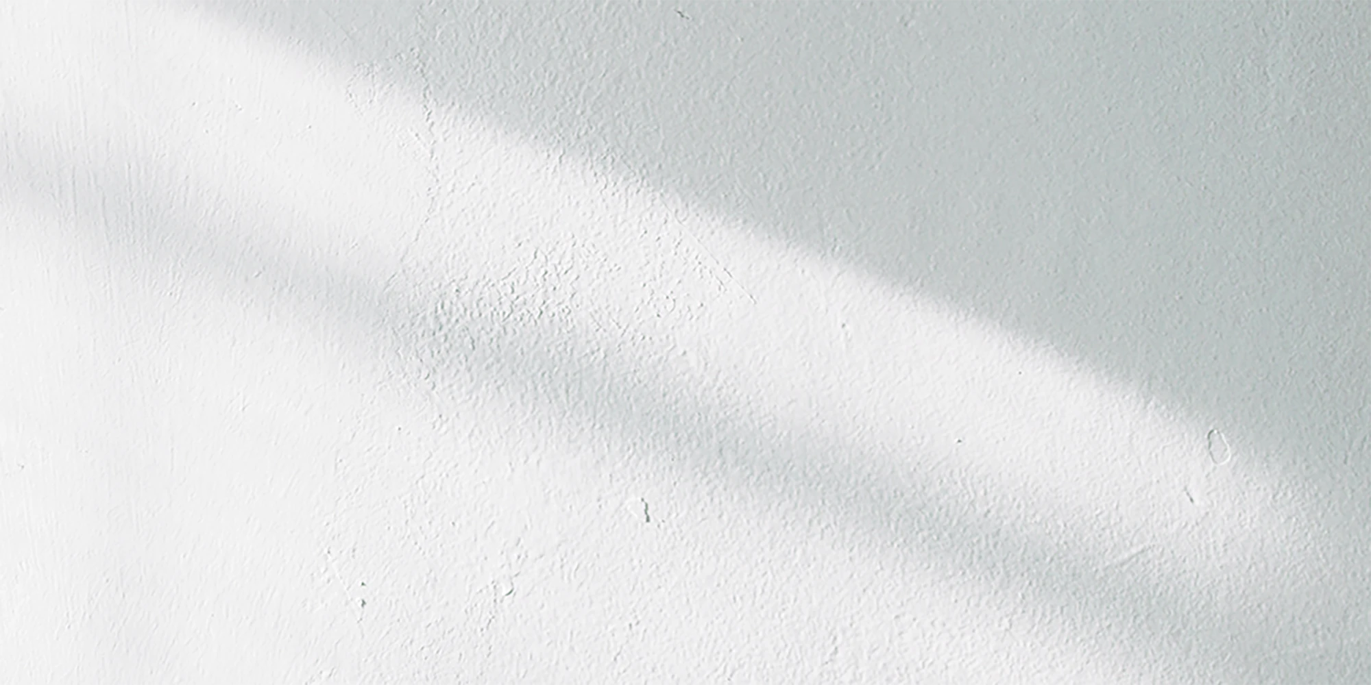 Gently textured white surface with soft light being cast across it.