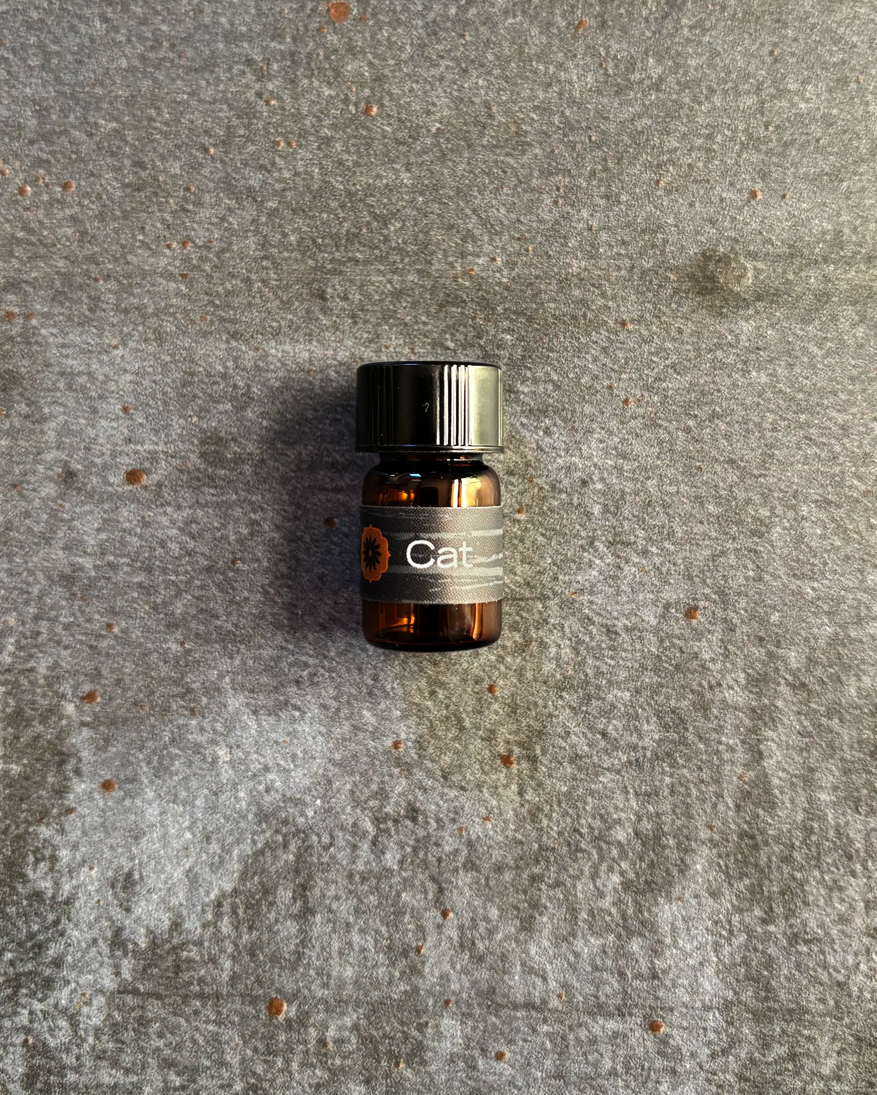 Small amber vial of BodyMantra Cat Power Animal oil blend on textured gray stone background.